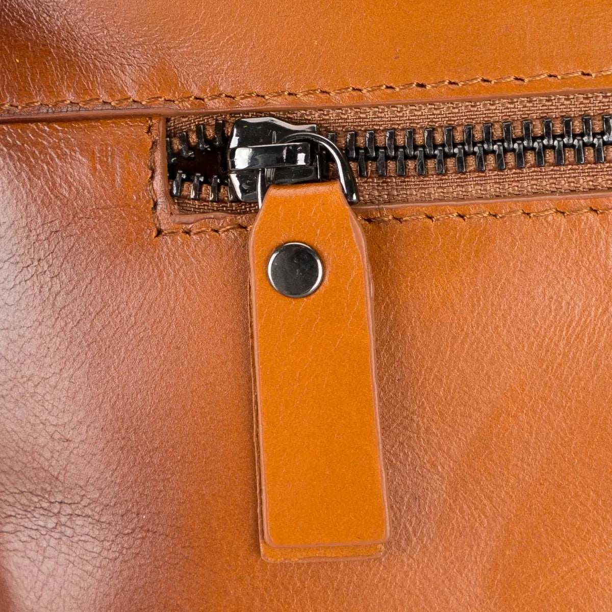 Close-up of a brown leather briefcase with a zipper and leather pull tab.