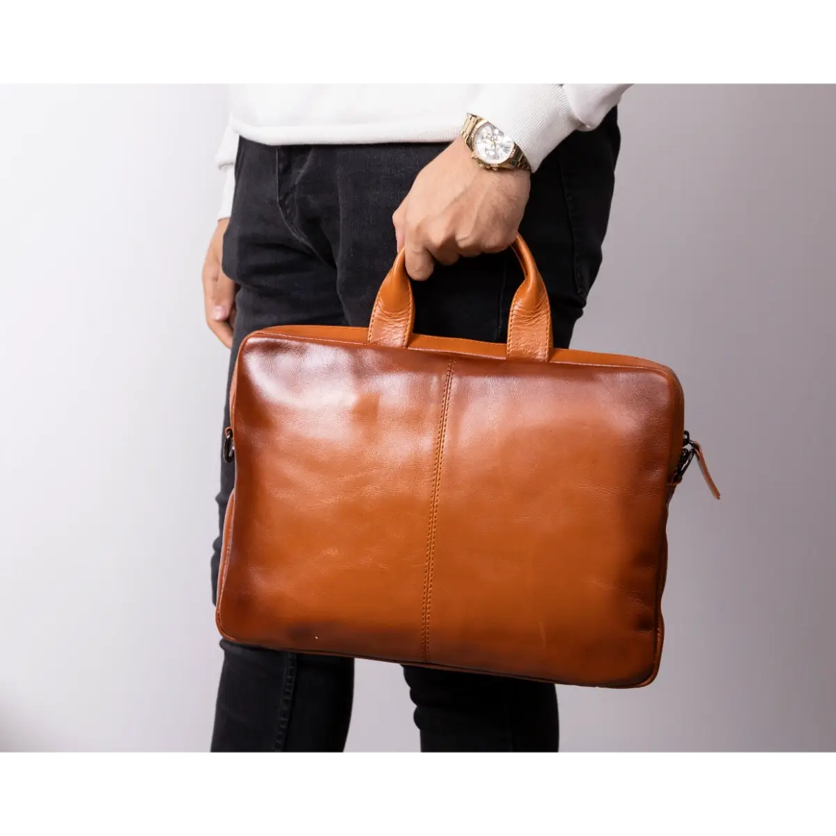 Person holding a Burnished Tan leather briefcase against a plain background