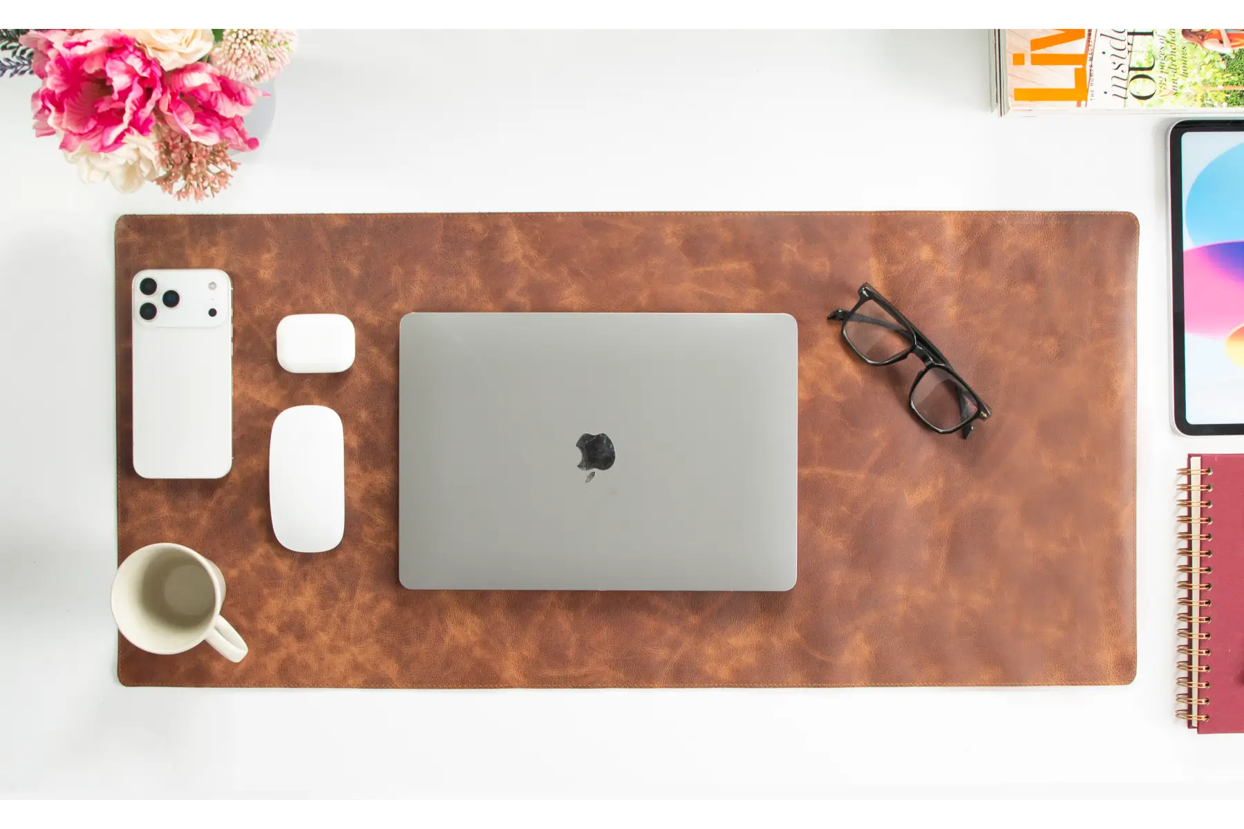 Brown leather desk mat with laptop, phone, and other items